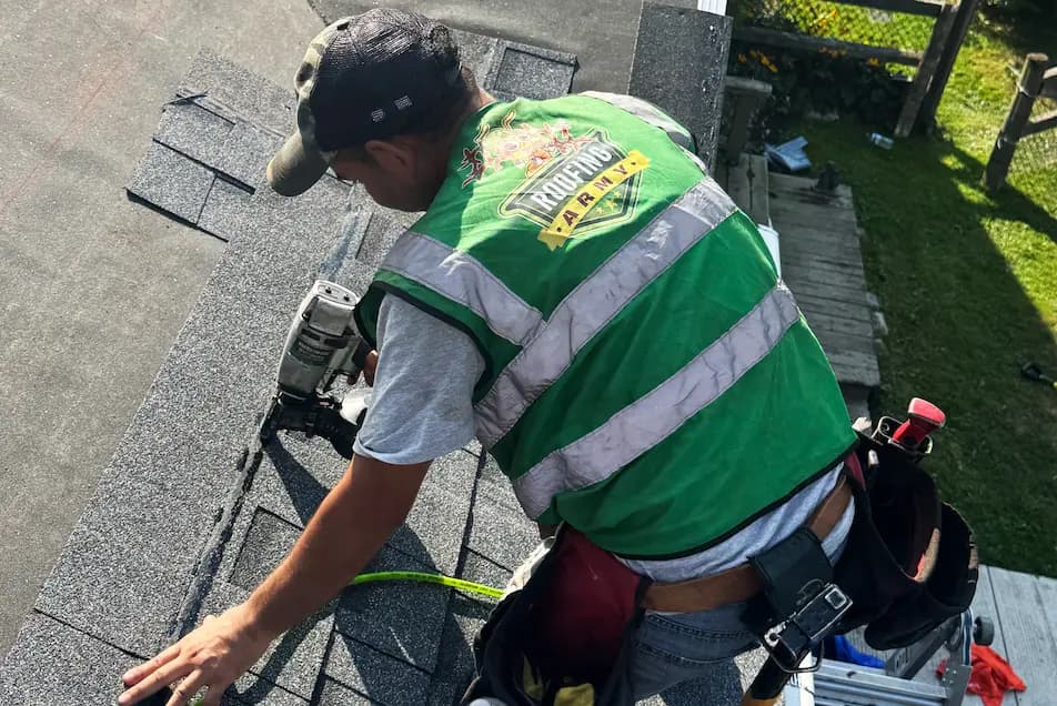 a roofer nailing a shingle on a roof replacement job in michigan