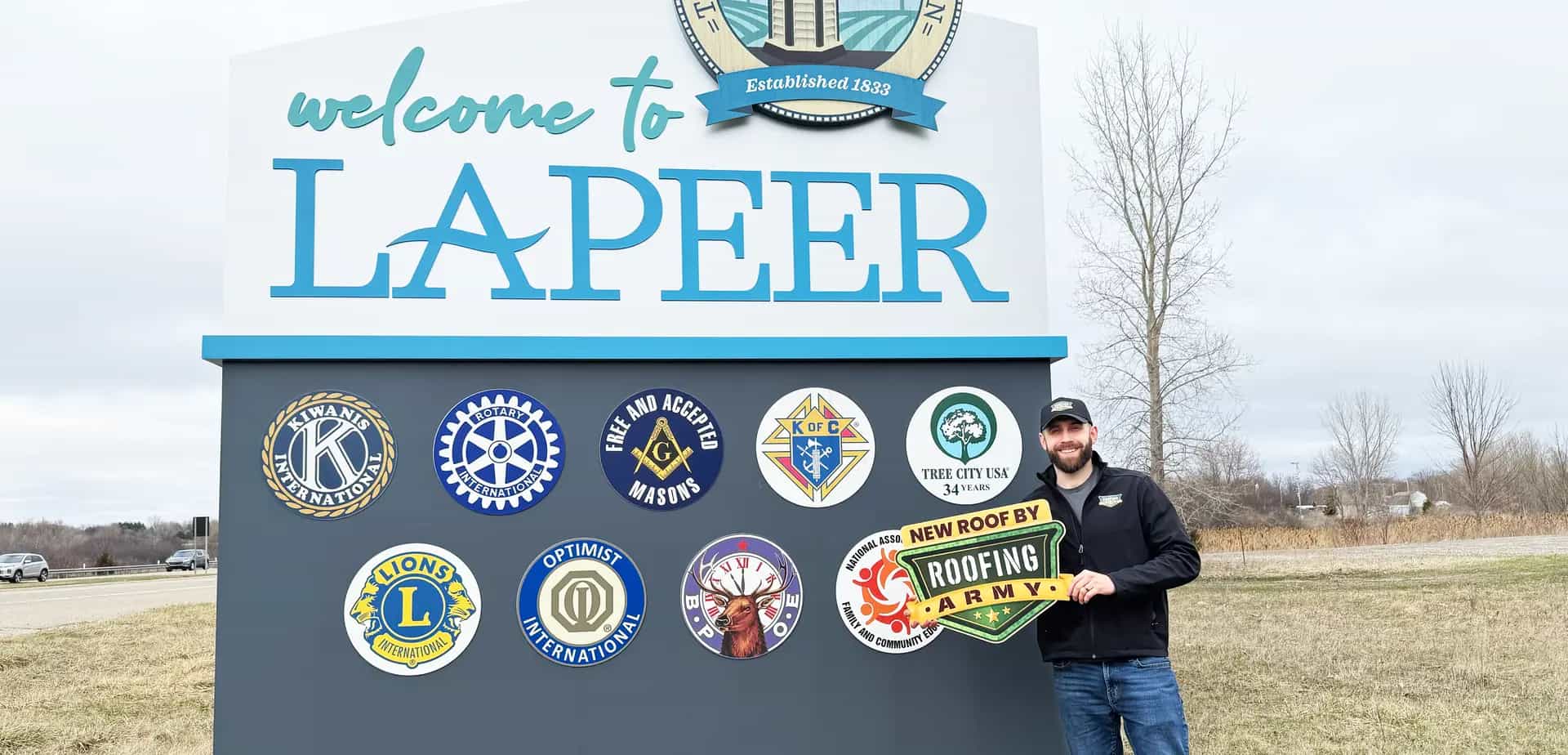 Aaron Scott, owner of Roofing Army, standing in front of the Lapeer welcome sign in Lapeer, Michigan Aaron Scott, owner of Roofing Army, standing in front of the Lapeer welcome sign in Lapeer, Michigan