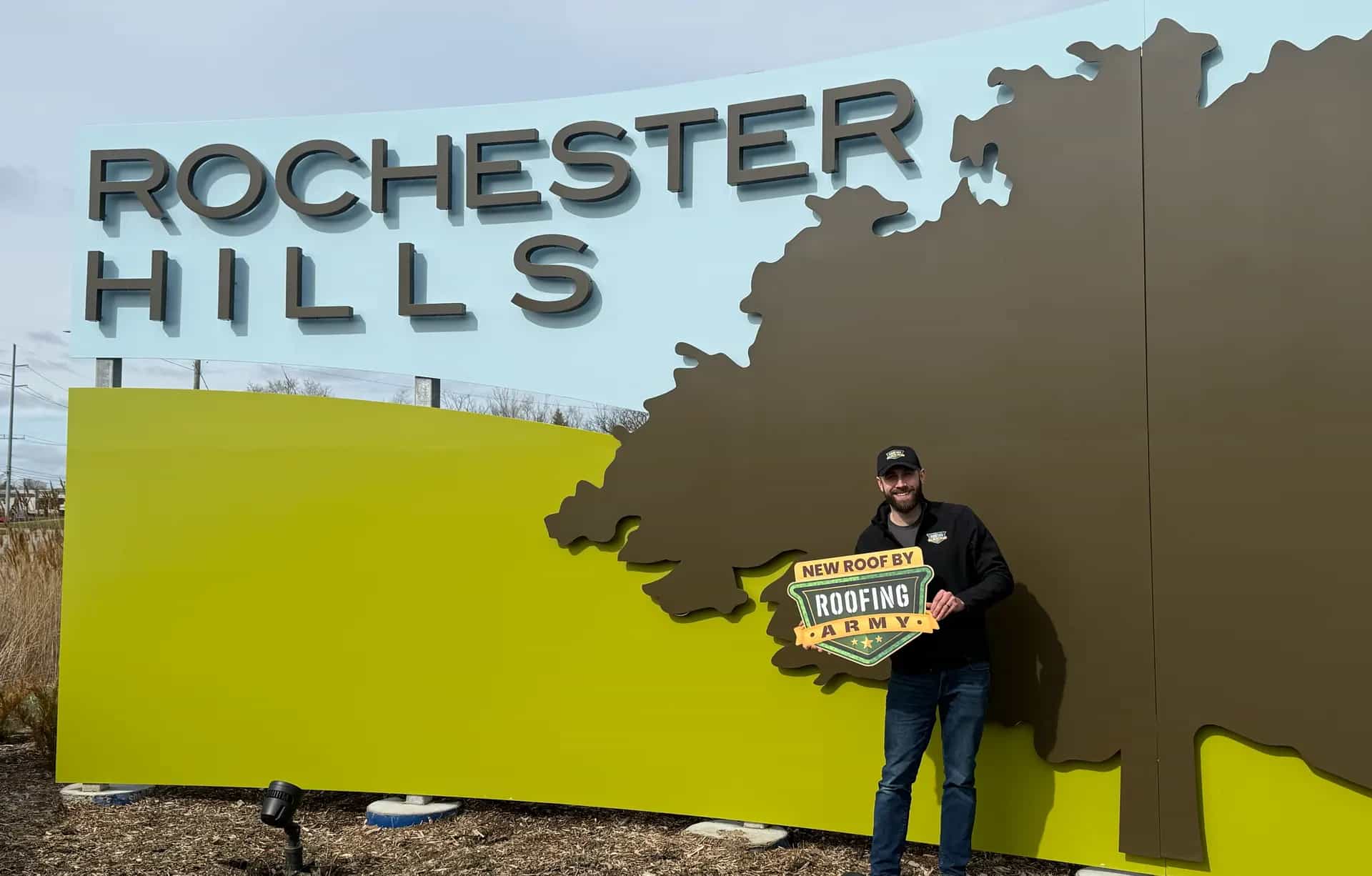 Aaron Scott, owner of Roofing Army, standing in front of the Rochester Hills city sign in Rochester Hills, Michigan Aaron Scott, owner of Roofing Army, standing in front of the Rochester Hills city sign in Rochester Hills, Michigan