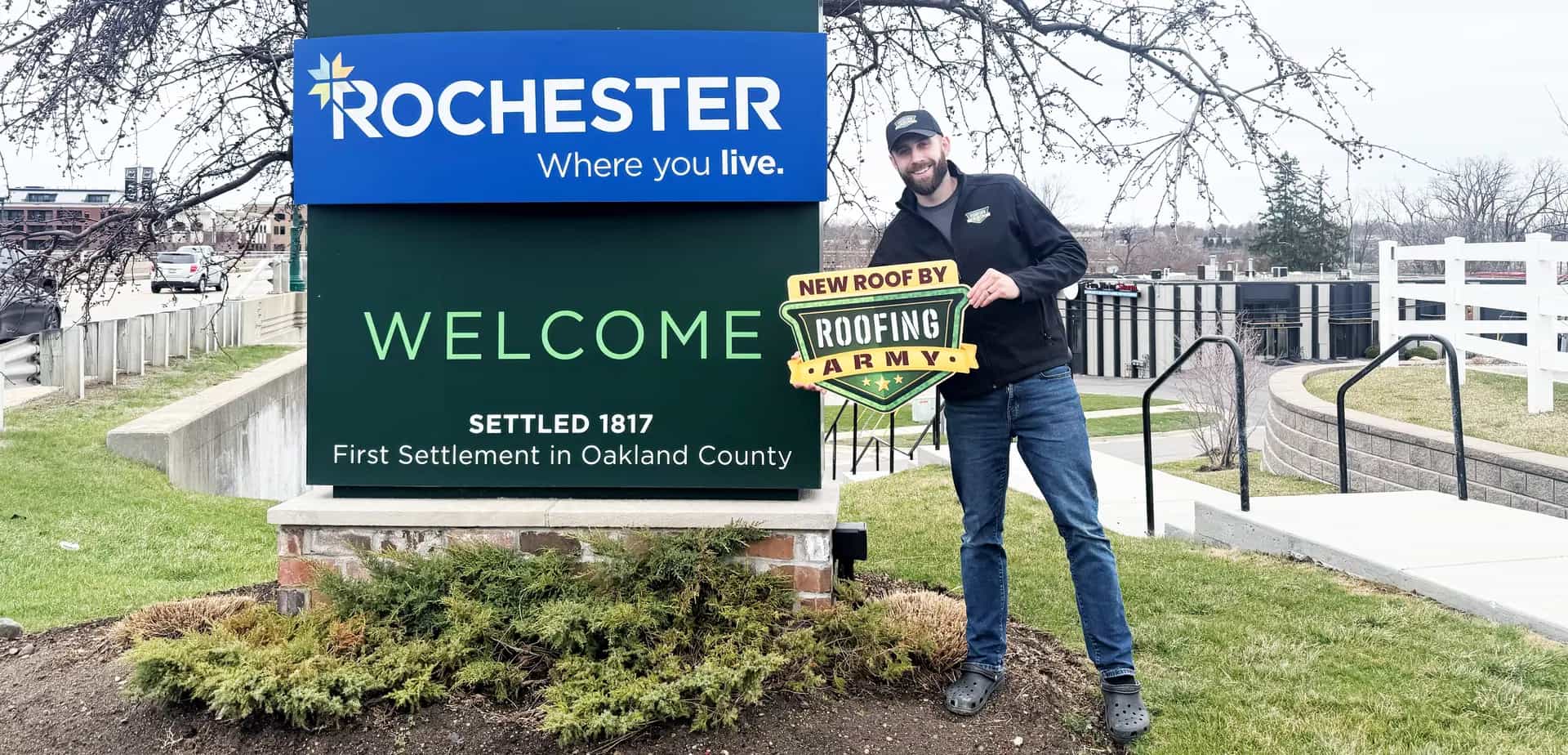 Aaron Scott, owner of Roofing Army, standing in front of the Rochester welcome sign in Rochester, Michigan Aaron Scott, owner of Roofing Army, standing in front of the Rochester welcome sign in Rochester, Michigan