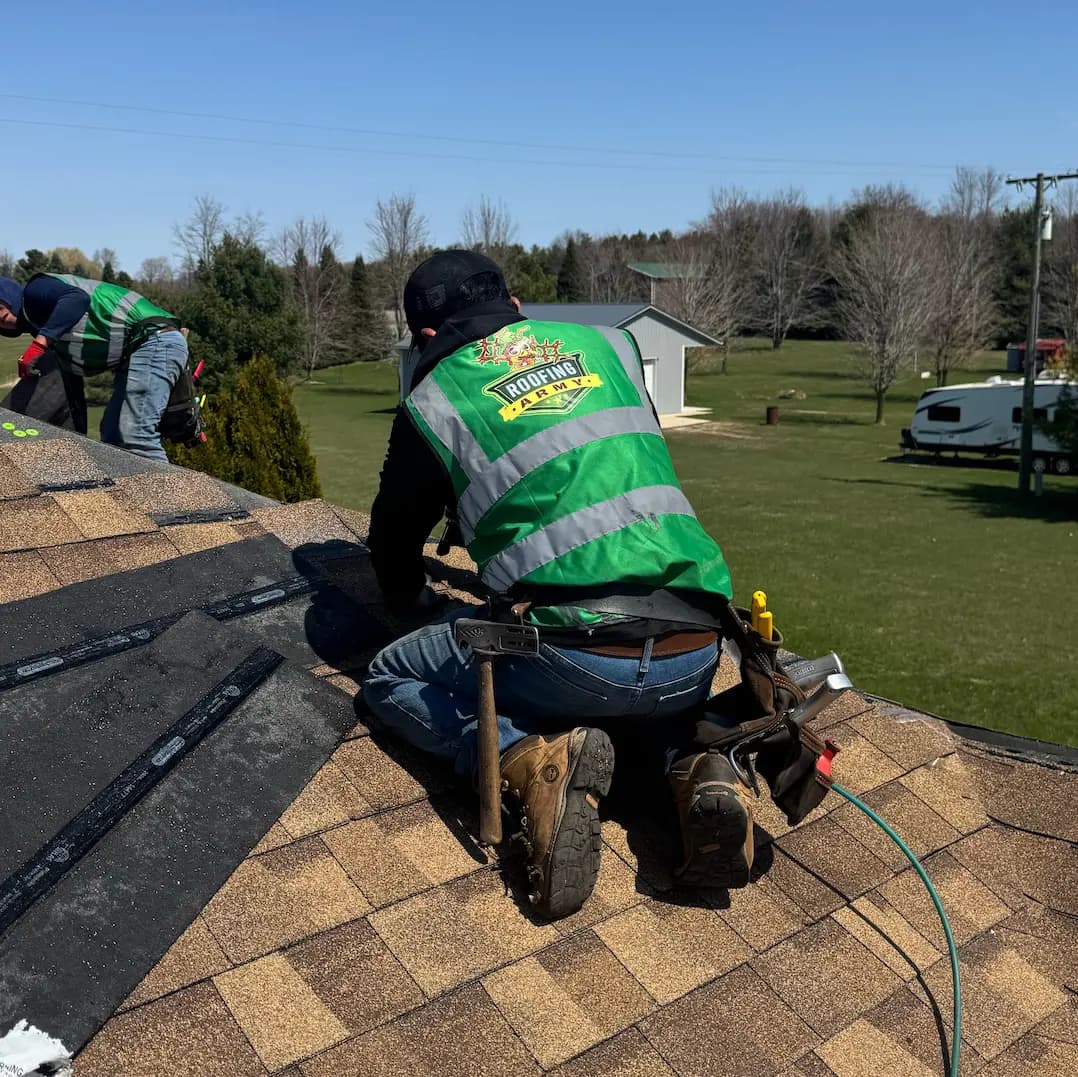 roofer wearing a green roofing army construction vest nailing hip shingles on a roof